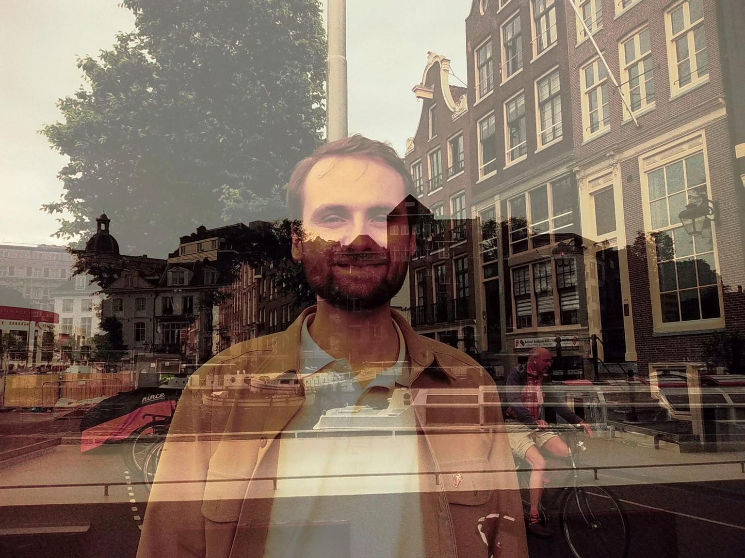 The developer of Open World, reflected in a window with an Amsterdam canal street